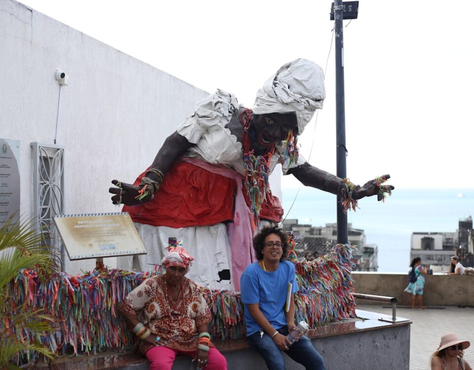 Quanto custa viajar pela Bahia sem gastar muito? A group of people sitting on top of a statue