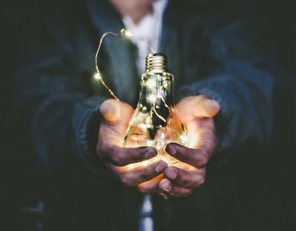 Ideias que viraram bilhões: invenções inesperadas que geraram fortunas man holding incandescent bulb