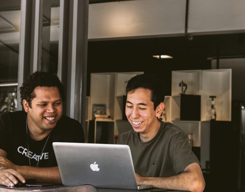 Empresas: uma consultoria de marketing pode aumentar o ROI? two smiling men looking at MacBook