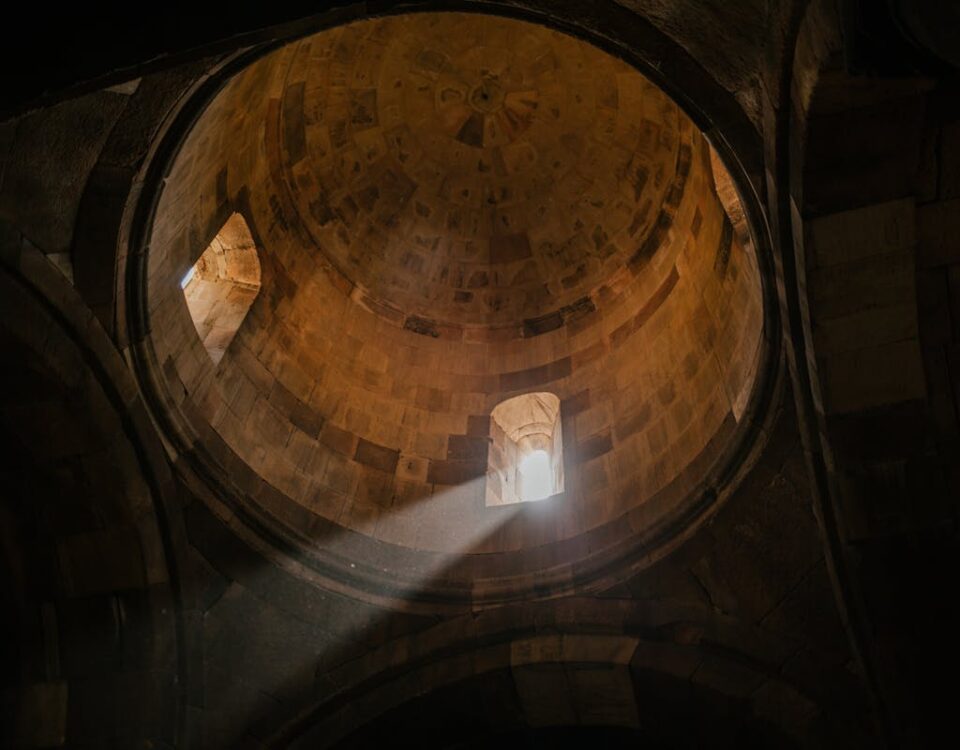 Vale a pena investir em viagens para lugares exóticos? From below of bright sunshine illuminating through window of dome in ancient stone cathedral