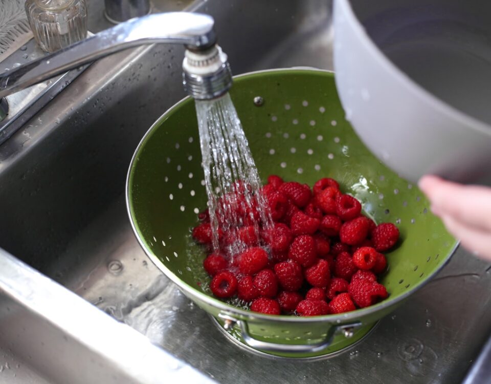 Dicas para economizar com serviços de desentupidora a person is washing raspberries in a sink
