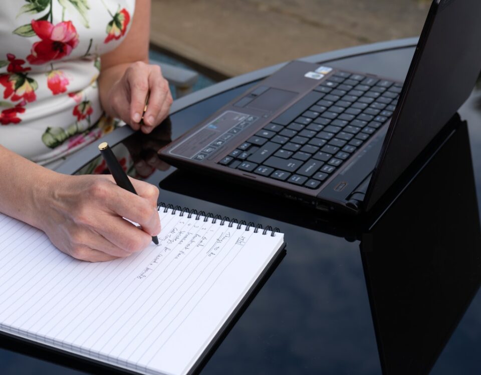 Cursos que podem aumentar seu salário em até 50% a person writing on a piece of paper next to a laptop