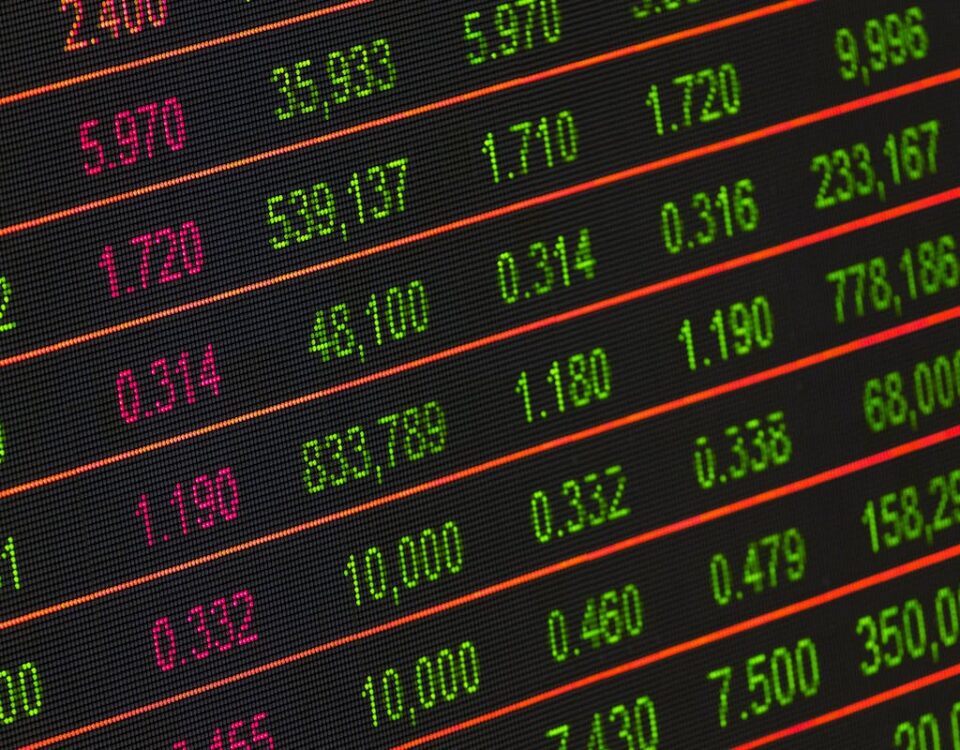 Investir em ações de fabricantes de armas é viável? Close-up of a digital stock market data display showing colorful financial numbers and trends.