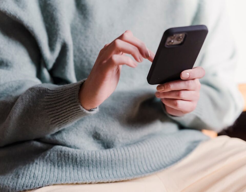 Economize recursos com atendimento automatizado no Whatsapp Crop faceless female in casual clothes using smartphone and touching screen while chilling at home