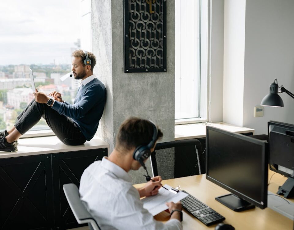 Como investir em cloud sem comprometer o orçamento da empresa Two call center agents working in a modern office, one seated at a computer and another using a tablet by the window.