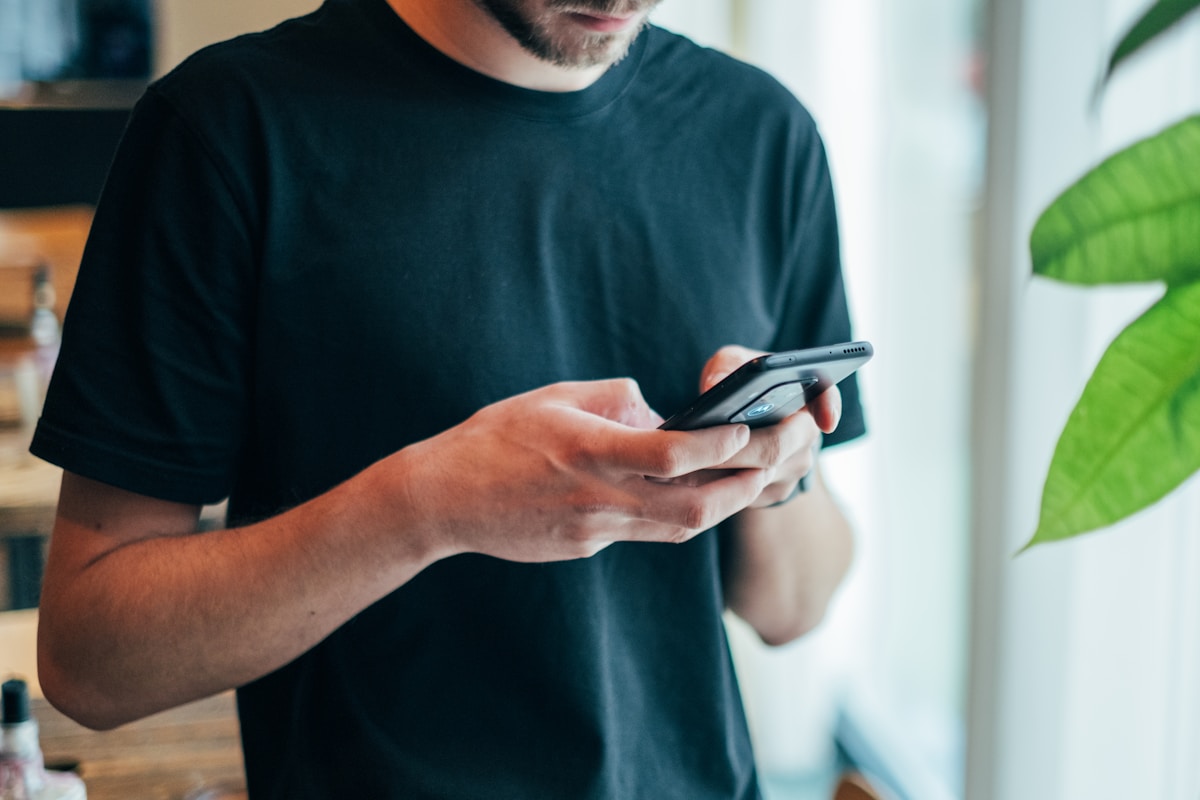 Como pagar menos e levar mais qualidade em tecnologia? man in black crew-neck top using smartphone