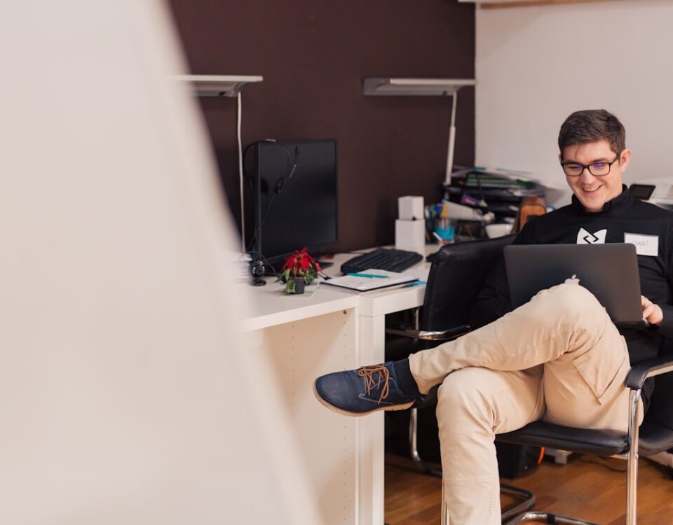 Como pagar menos e levar mais qualidade em tecnologia? man smiling while sitting and using MacBook