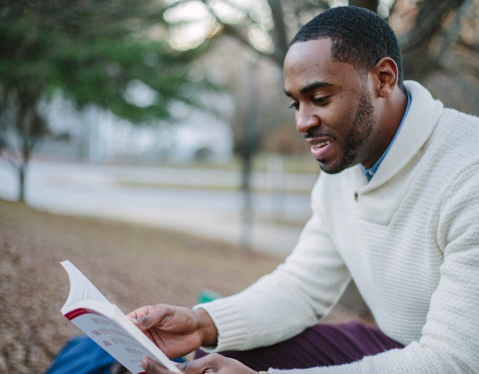 Cursos que ajudam a melhorar sua educação financeira man wearing white sweater while reading book
