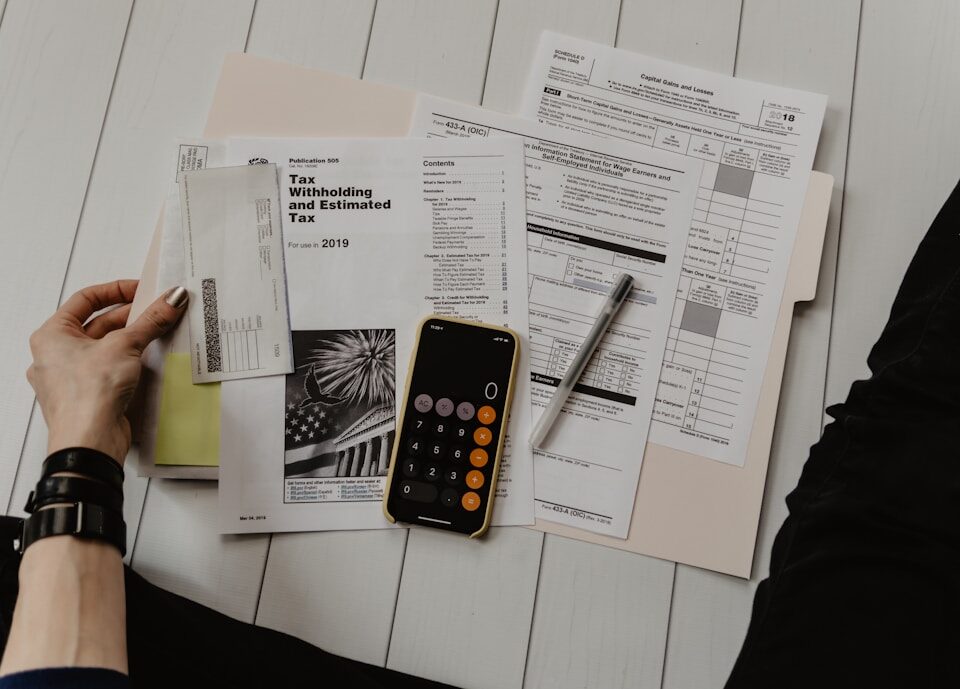 Finanças pessoais e empresariais: como equilibrar as contas person holding paper near pen and calculator