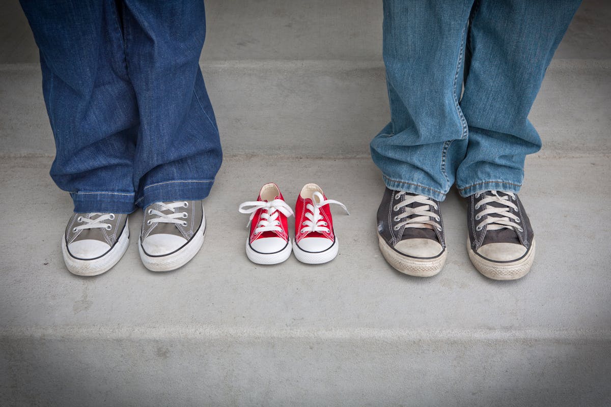 Casual family footwear representing growth with baby sneakers between adults.