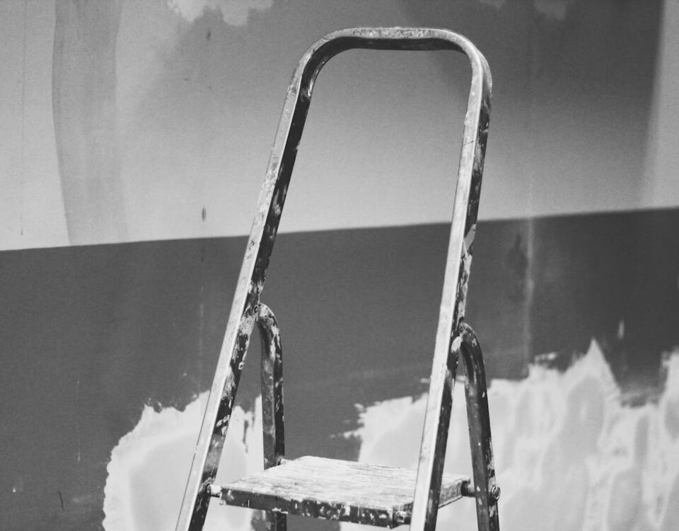 Dicas econômicas para proteger paredes e telhados Black and white photo of an old ladder leaning against a painted and textured wall.