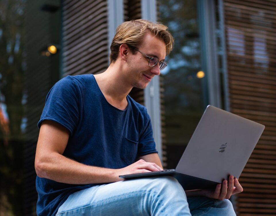 Vale a pena investir em cursos profissionalizantes? A young man sitting outdoors in Leiden, Netherlands, working on a laptop.