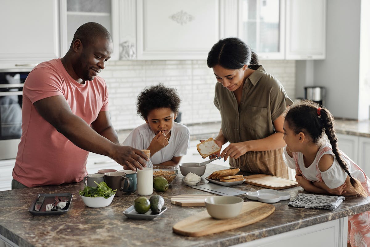 Economizar na cozinha sem abrir mão do sabor A joyful family enjoys preparing a healthy meal together in their modern kitchen.