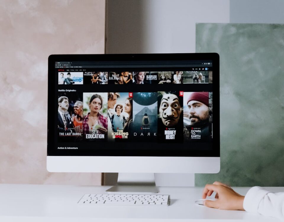 Vale a pena assinar mais de um serviço de streaming? A modern workspace featuring a desktop screen displaying popular streaming series on Netflix.