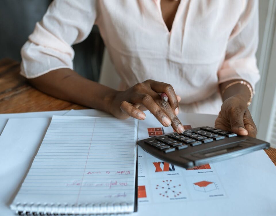 Estratégias para economizar com seguros sem perder cobertura A professional woman calculating finances at a desk with charts and a calculator.