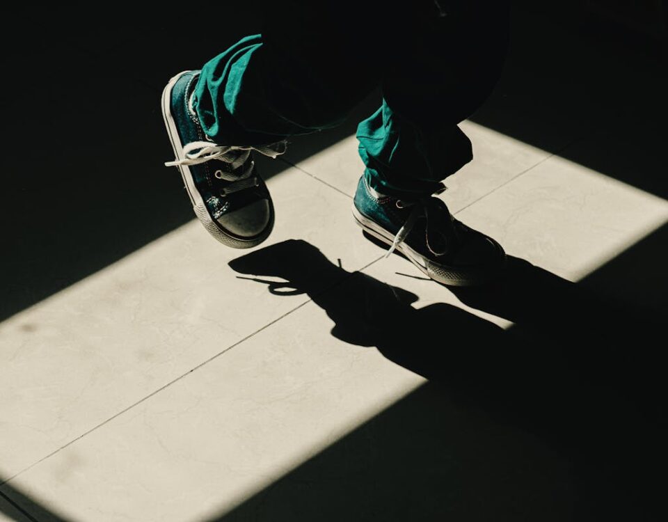 Comprar calçados infantis: Como economizar sem abrir mão da qualidade Silhouette of a child walking in sunlight with visible shadows and sneakers.