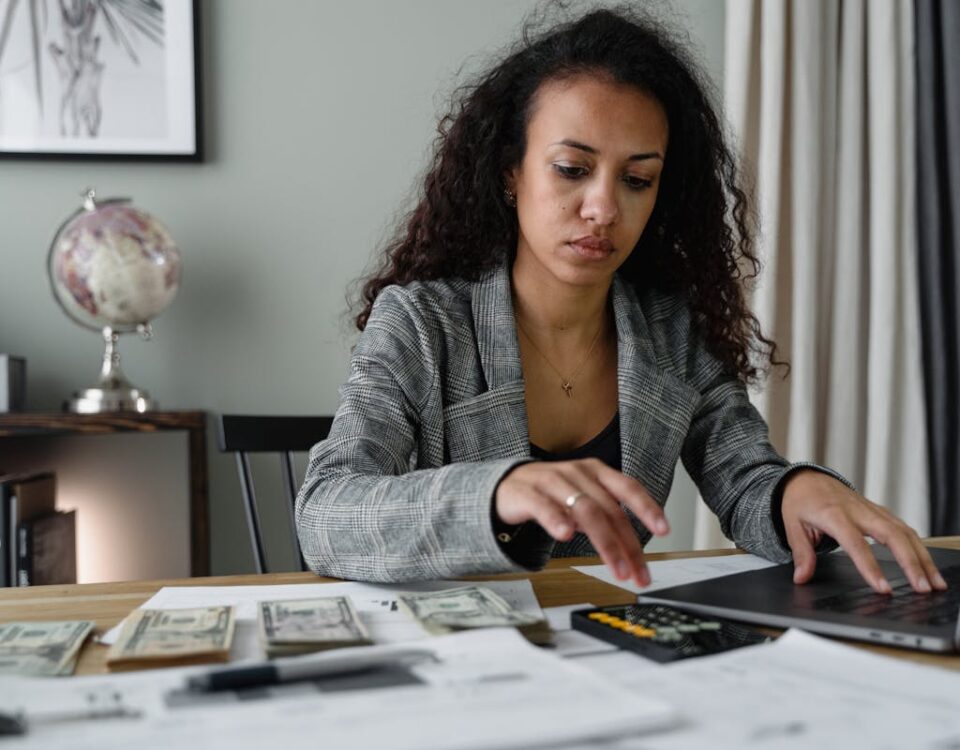 Automação comercial: Como reduzir custos e aumentar lucros? Professional woman analyzing financial documents and counting cash at office desk.