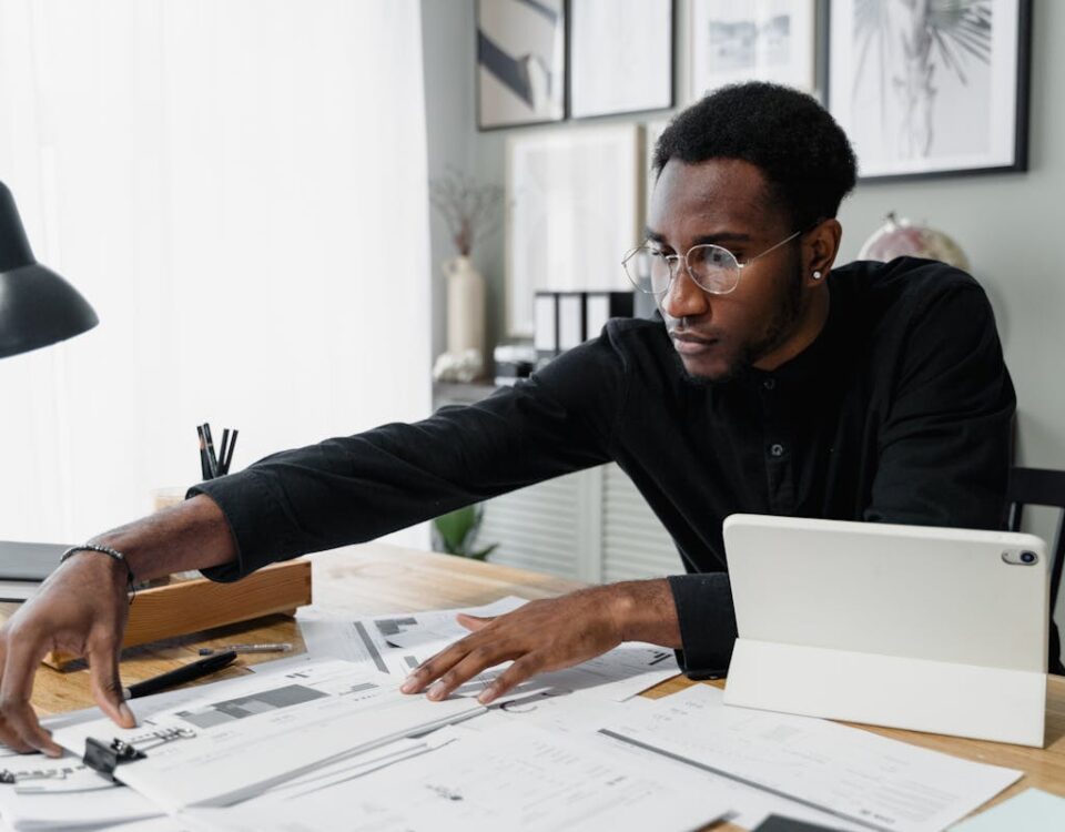 Quanto custa tirar a CNH? Business professional working at desk reviewing financial documents with digital tablet.