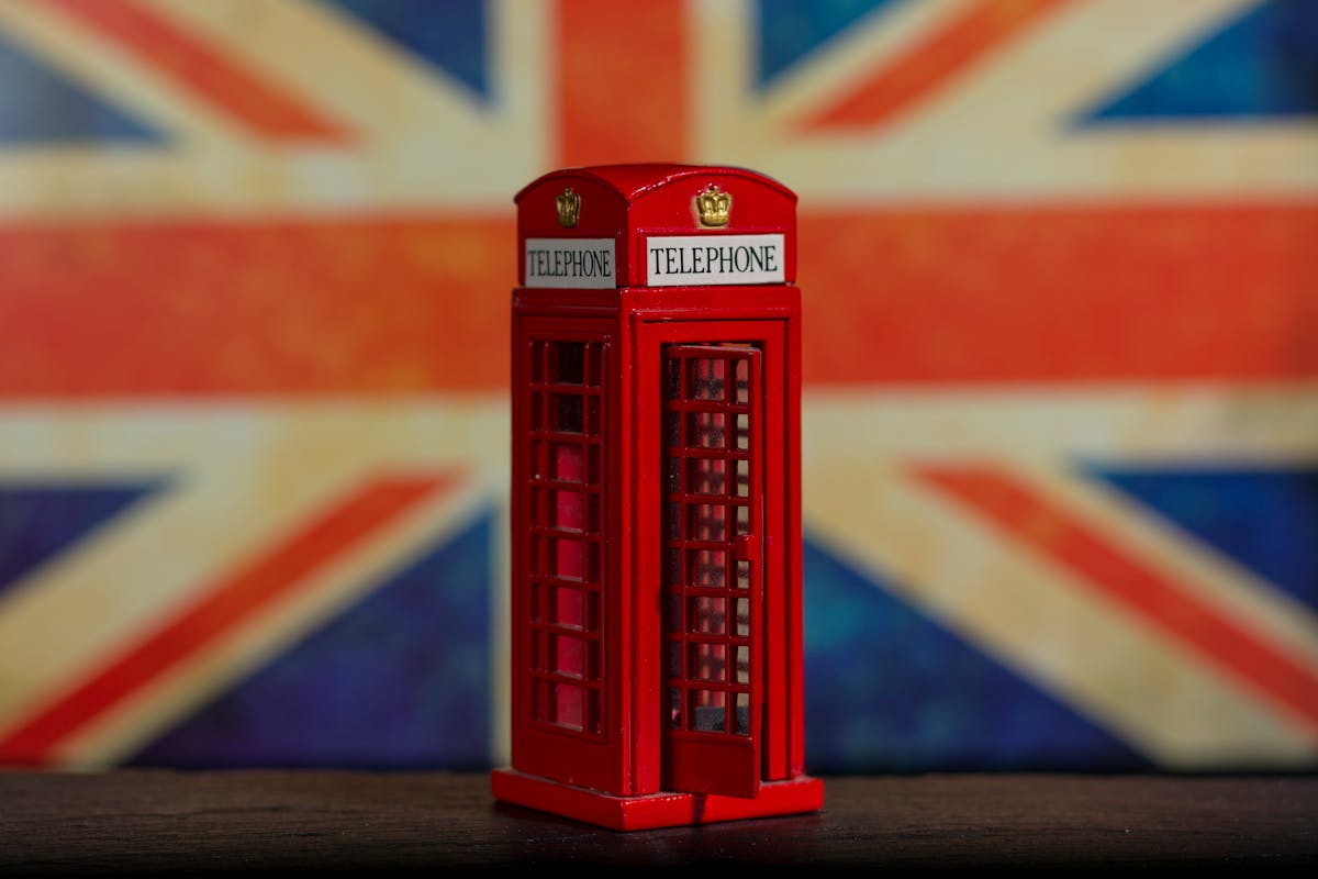 Como economizar na compra de lembranças de viagem A miniature red telephone booth with a Union Jack background, symbolizing iconic British heritage.