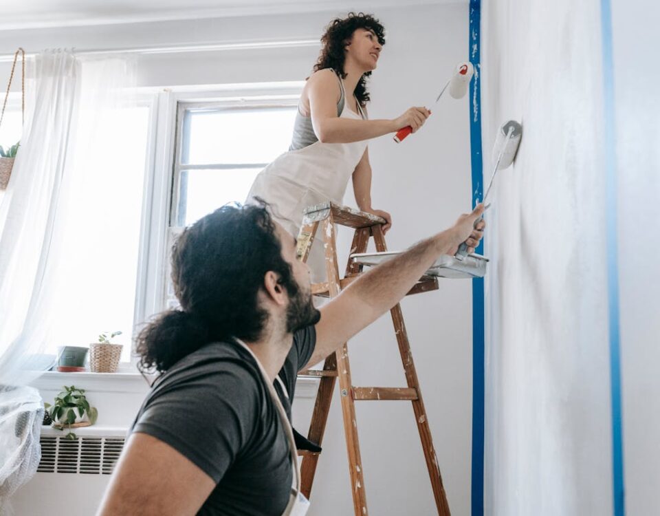 Como economizar na compra de itens para decoração da casa A couple engaged in a joyful home renovation, painting walls together.