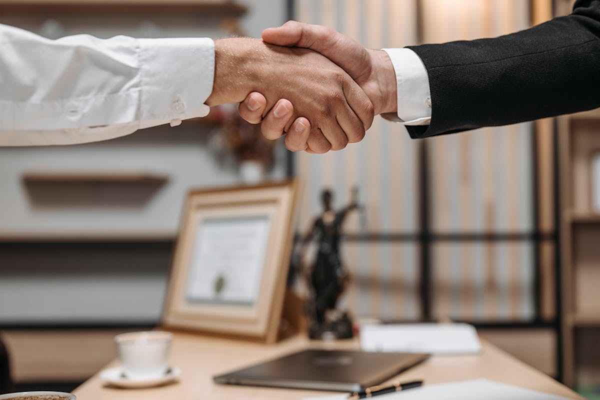 Quanto custa contratar um advogado criminal? Close-up of a handshake between two professionals in a modern office setting, emphasizing partnership and agreement.