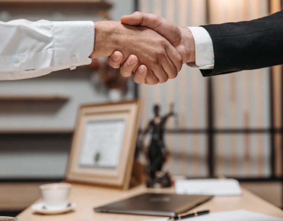 Quanto custa contratar um advogado para plano de saúde? Close-up of a handshake between two professionals in a modern office setting, emphasizing partnership and agreement.