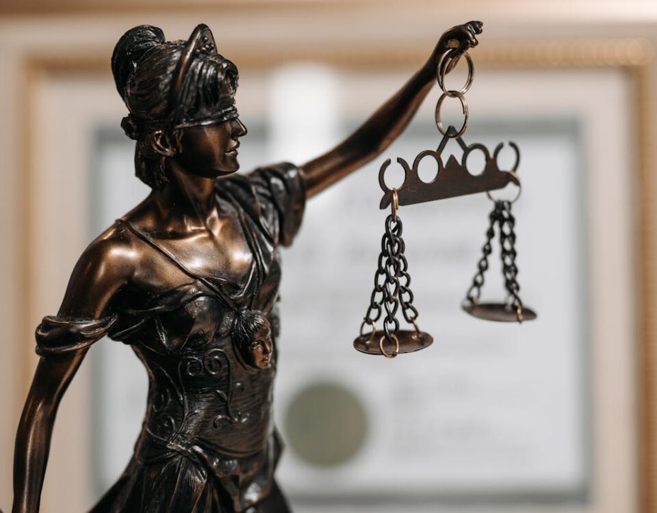 Quanto custa contratar um advogado criminal? Close-up of a bronze Lady Justice statue holding scales in an office environment.