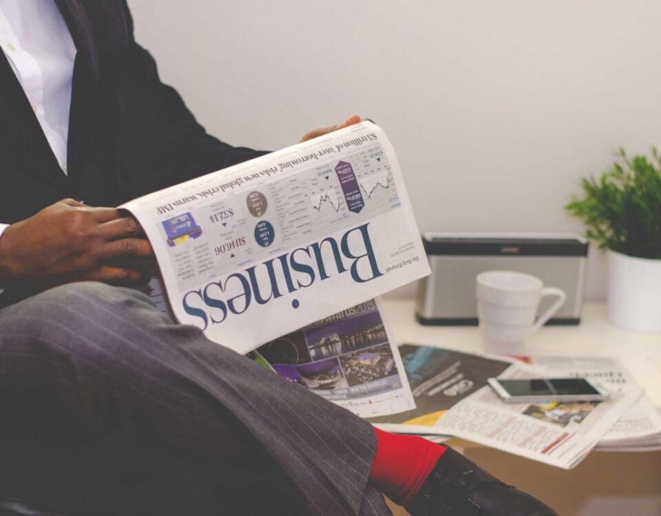 Notícias financeiras: como identificar as mais confiáveis? Businessman reading a financial newspaper at a desk, highlighting finance and commerce theme.