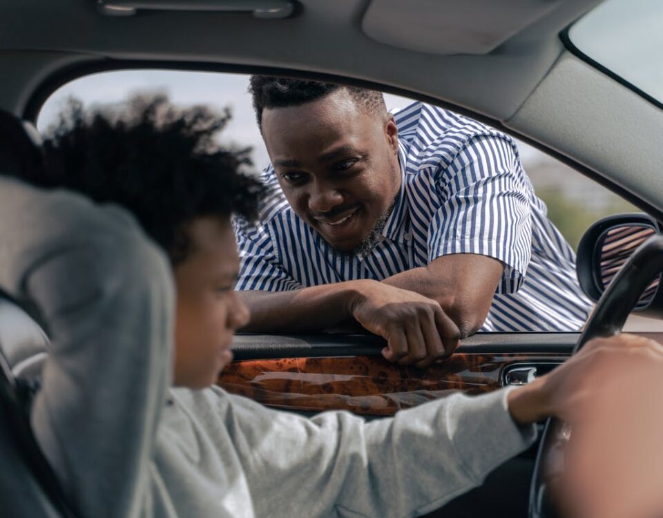 Vale a pena investir em aulas extras de direção? Father teaching his son how to drive, bonding and learning together.