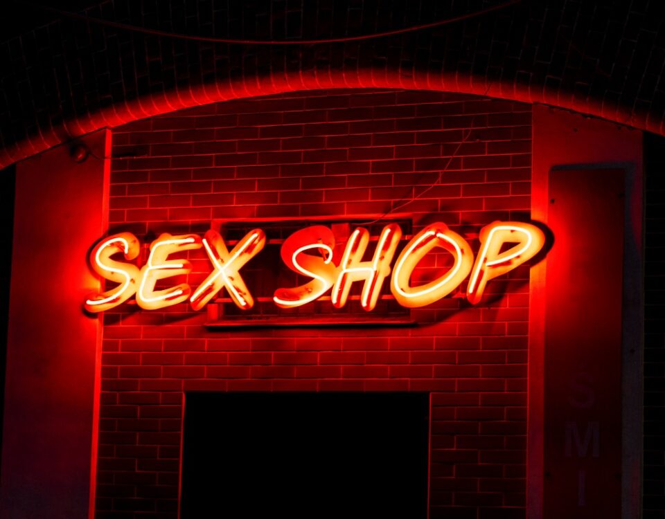 O mercado adulto é um bom investimento? a neon sign that reads sex shop on a brick wall