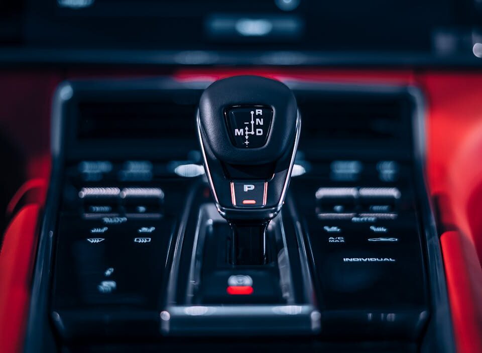 É mais econômico dirigir manual ou automático? Focus on a sleek car gear shift lever in a luxury vehicle interior.