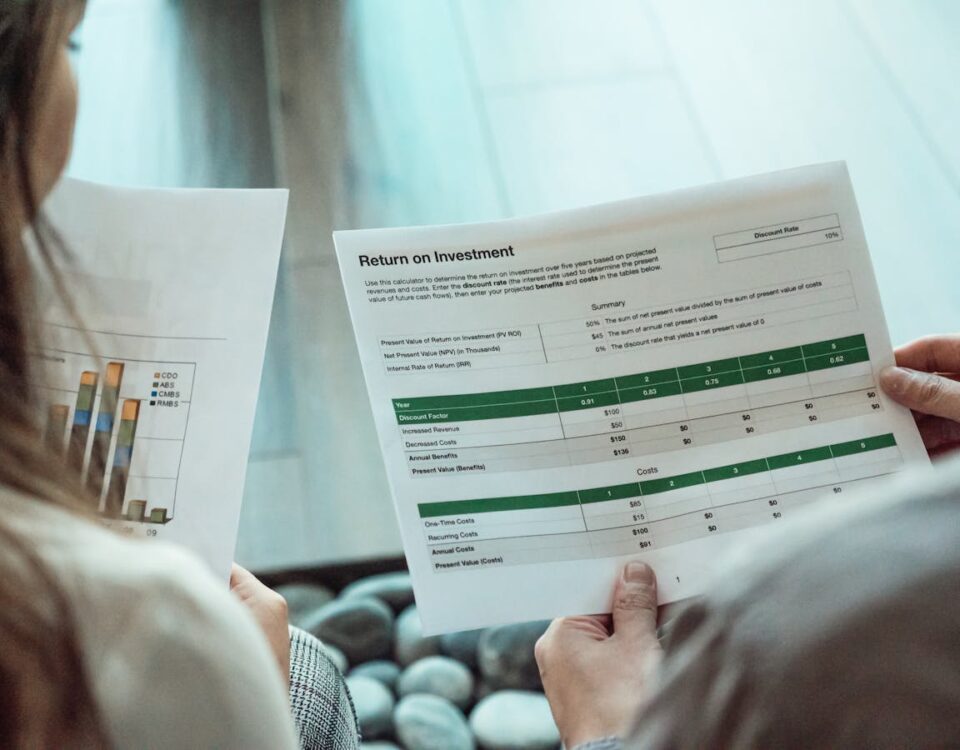 Como maximizar ROI em campanhas de marketing Close-up of two individuals analyzing financial documents related to return on investment.
