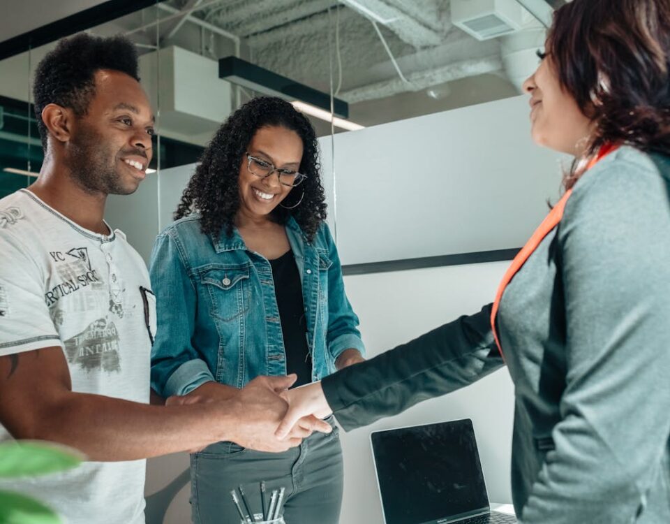 Quanto economizar ao contratar um advogado de forma estratégica? Smiling couple shaking hands with advisor in modern office.