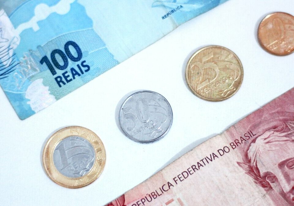 Cédulas e moedas de real sobre uma mesa clara