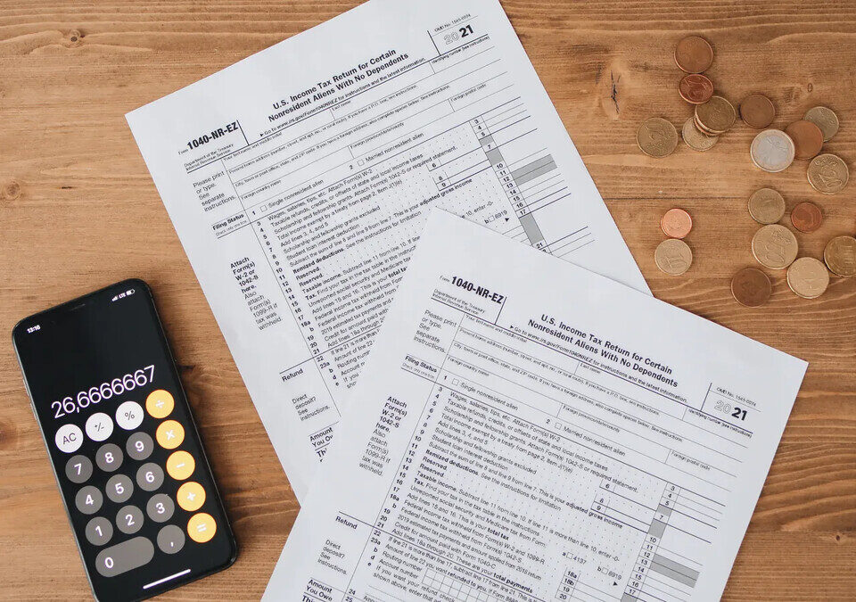 Calculadora e moedas ao lado de documentos tributários