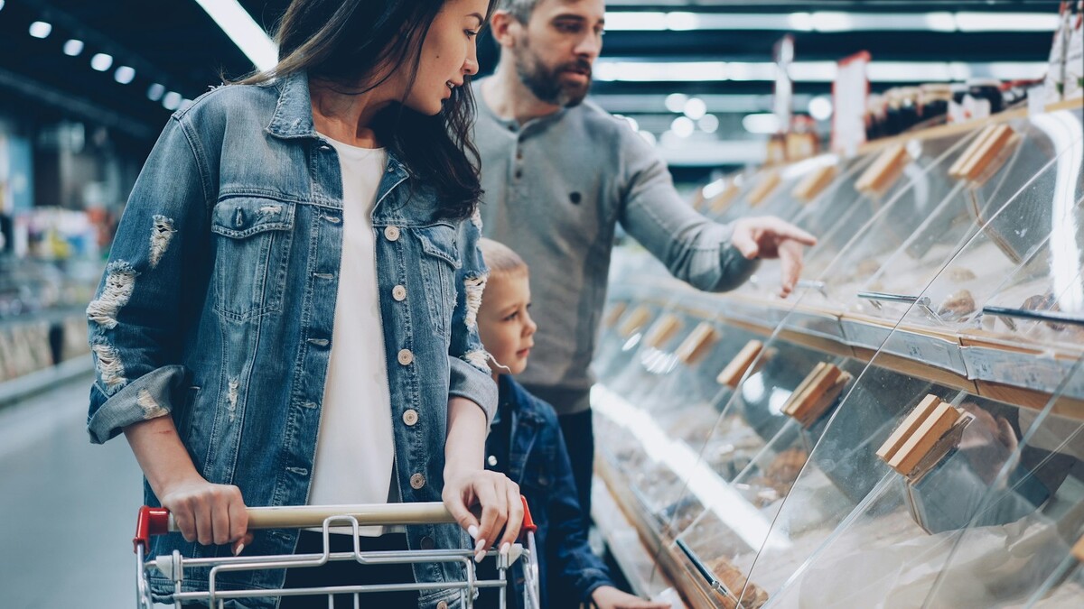 Família fazendo compras em um supermercado, empurrando um carrinho