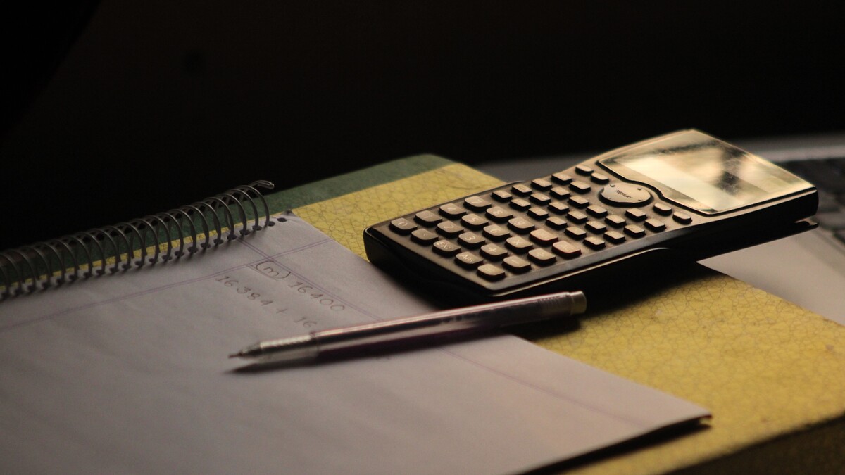 Como planejar o orçamento para entretenimento adulto em Curitiba? Calculadora e caderno usados para organizar valores de um orçamento.