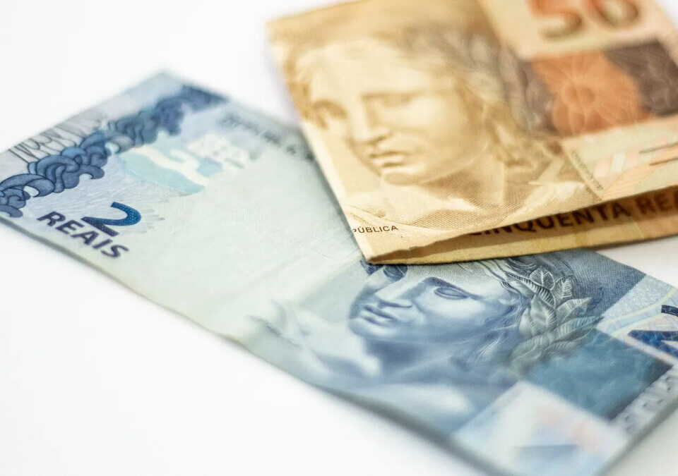 Cédulas de 2 e 50 reais sobre fundo branco