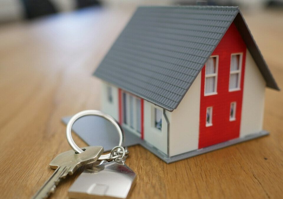 Miniatura de casa branca e vermelha sobre mesa de madeira