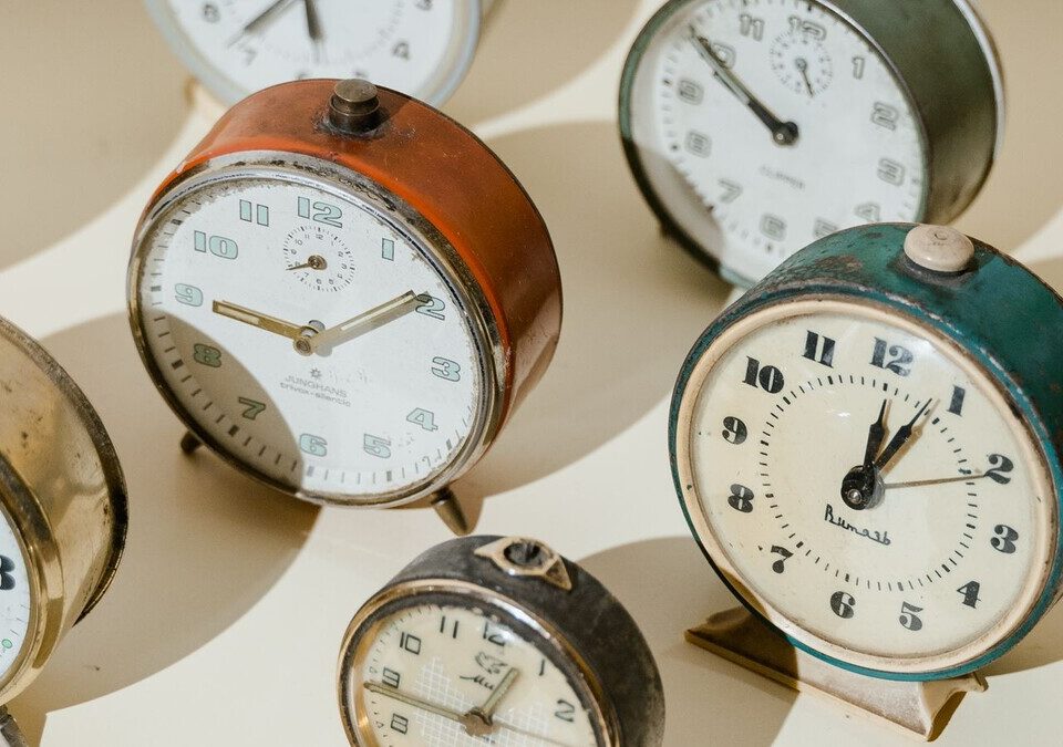 Relógios despertadores antigos enfileirados sob luz quente