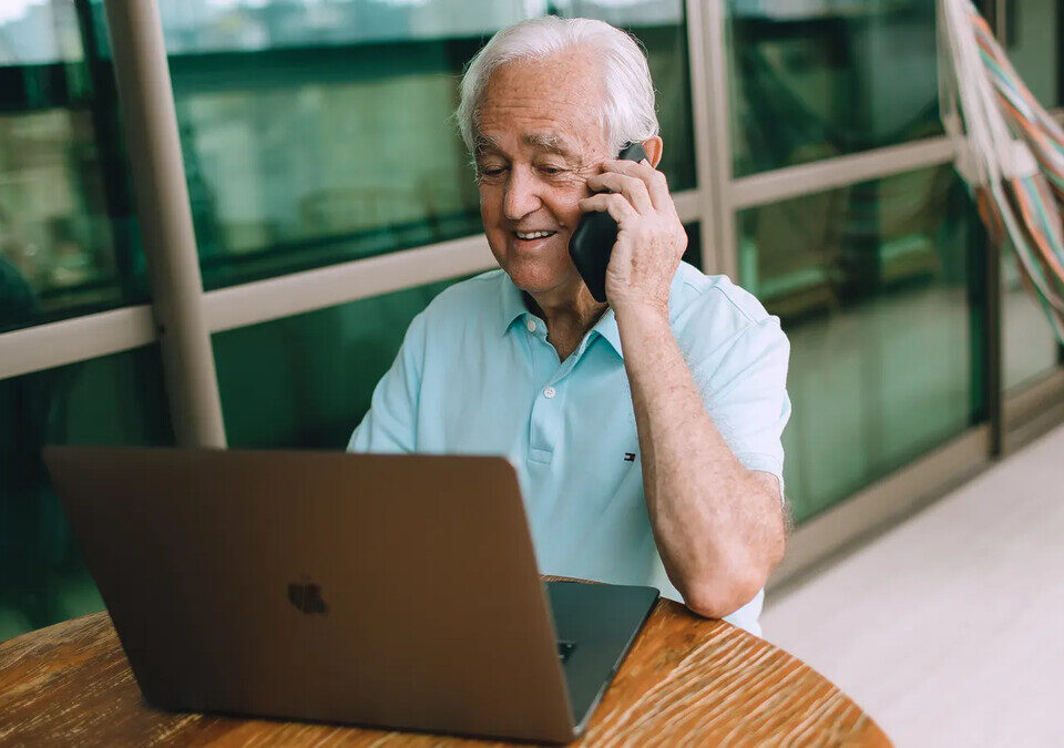 Idoso utiliza notebook e conversa por telefone