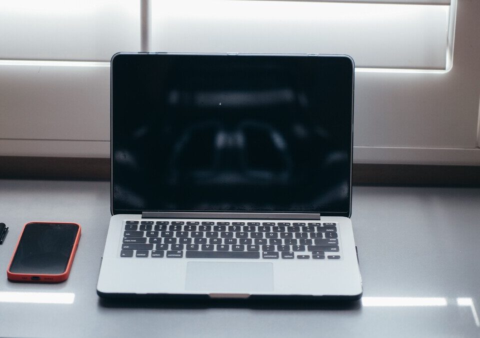 Notebook e celular sobre mesa para consulta de serviços digitais