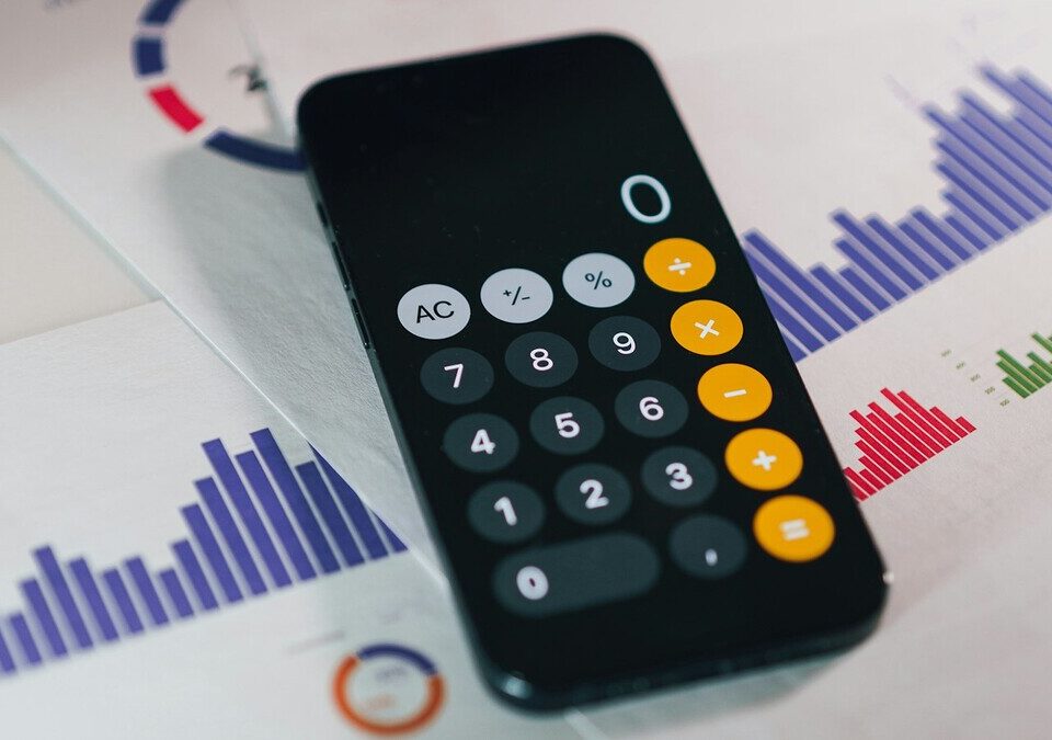 Calculadora no smartphone sobre relatórios financeiros em uma mesa