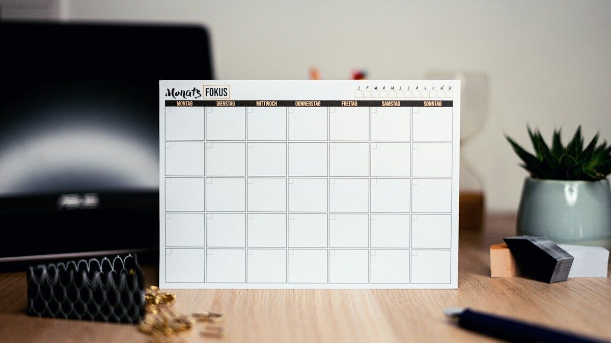 Quanto custa a hora de trabalho para a empresa além do salário? Planejador mensal branco sobre uma mesa de trabalho, usado para contar dias úteis e feriados