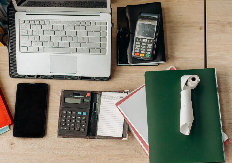 Mesa de trabalho com calculadora, computador e documentos para organização financeira