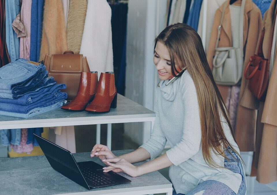 Empreendedora trabalhando no notebook em uma loja de roupas